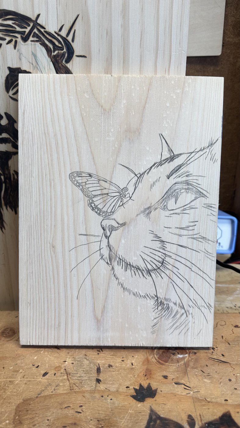 Butterfly Kiss — a cat with a butterfly on its nose, sketched on wood, ready to burn