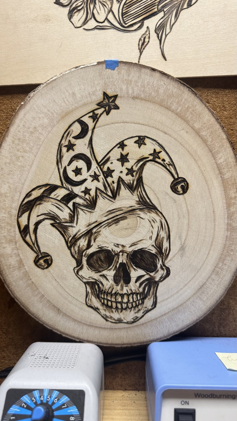 The finished jester skull piece, fully shaded, on a wood round