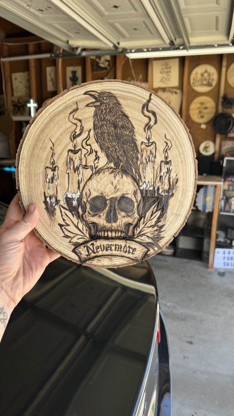 Nevermore — woodburned raven perched on a skull among dripping candles, held up in the studio