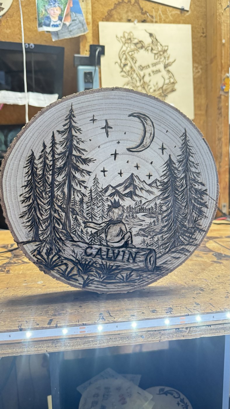 Little Prince — finished woodburning of a boy in a crown sitting on a log under the moon and stars, named Calvin
